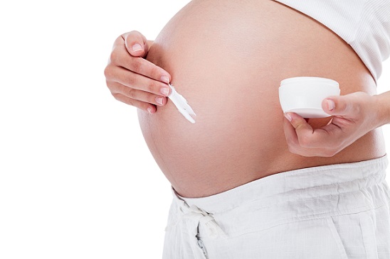 Donna incinta che si mette la crema sulla pancia