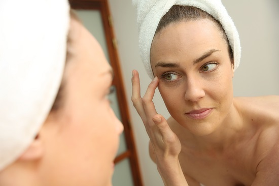 donna-che-si-spalma-crema-con-peptidi-allo-specchio
